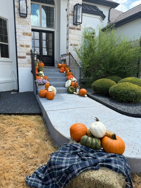Celebrate Collection pumpkins and gourds lining a stone staircase walkway with hay bale