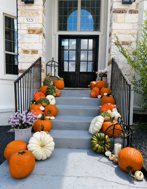 Celebrate Collection pumpkins lining a stone home entry in daylight
