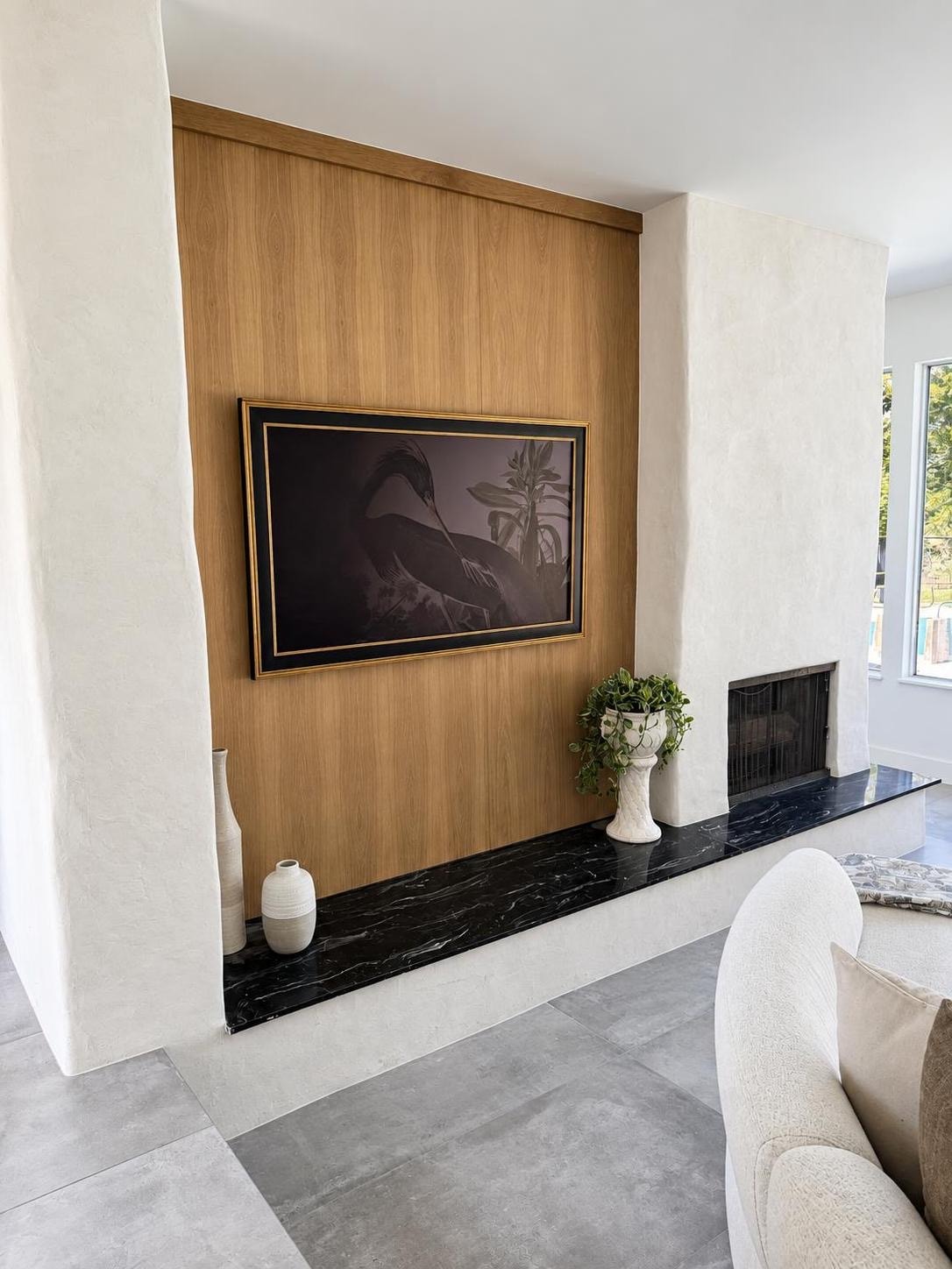 Open-plan living room with a wood-slat feature wall, large-format tile flooring, and floor-to-ceiling windows overlooking the landscape.