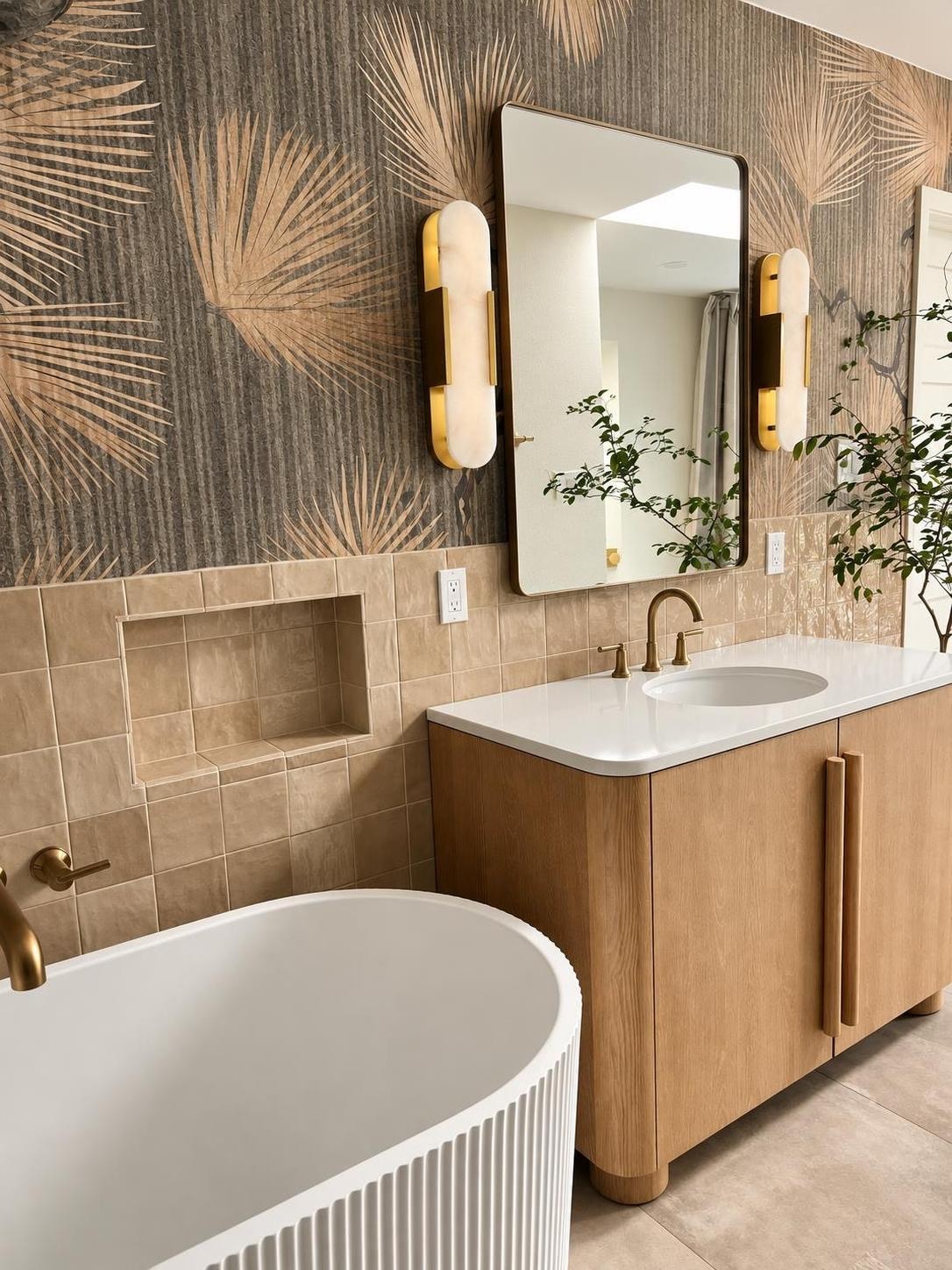 Secondary bathroom with a warm wood double vanity, matte black fixtures, stone-look tile wall, and a vertical sconce between two mirrors.