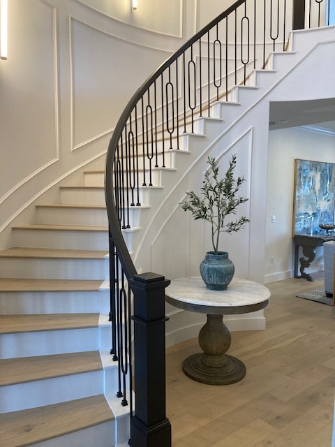 Lake Travis Project curved staircase with black railing, light wood flooring, and round entry table
