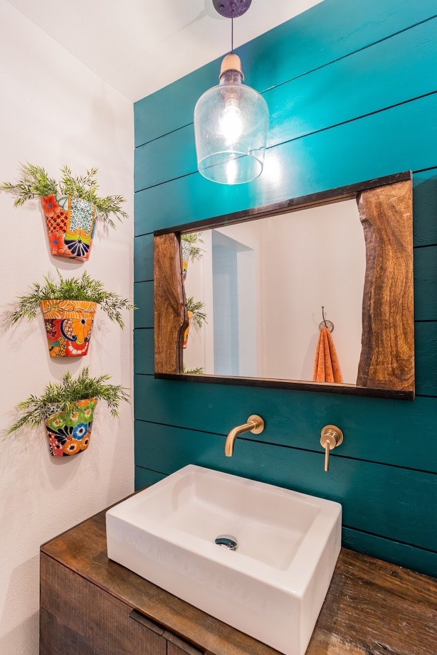 Colorful bathroom vanity with teal paneling, a rustic wood mirror, and a vessel sink.