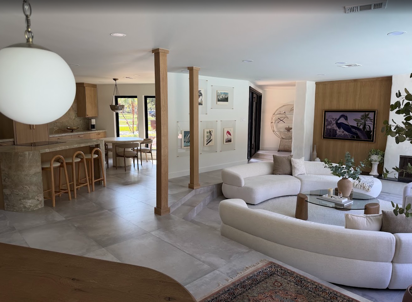 Open-plan living room and kitchen with warm wood cabinetry, stone finishes, and contemporary furnishings.